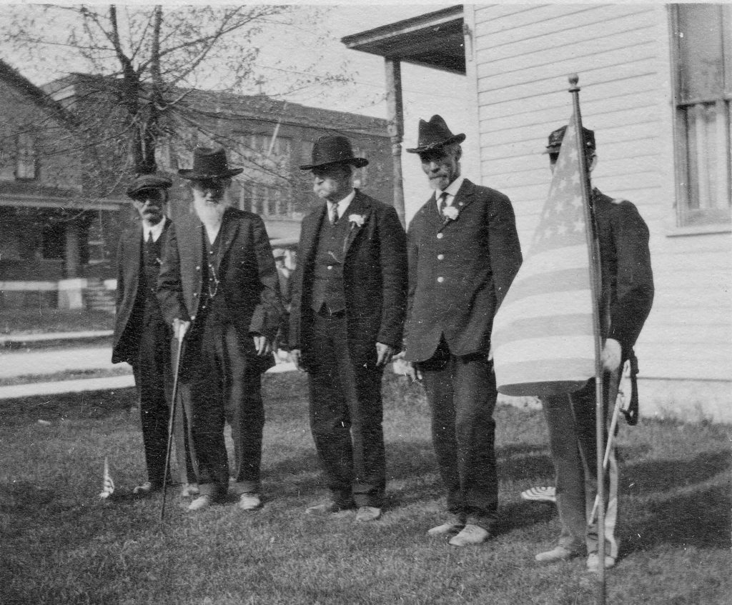 Civil War veterans gathered at the home of Major Wright E. Clarke on Lake Street across from the old St. Frances De Sales School. From left to right: Unidentified, George Sorter, John Cowman, Mr. Gear and Spanish American War veteran Charles W. Adkins (hidden behind the flag). Niles and Helmka Family Collection.