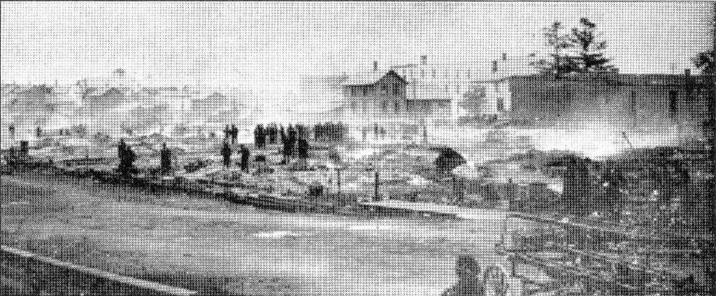The devastation wrought by the fire is evident on the morning of September 16, 1893. Manistique’s hook and ladder wagon can be seen in the foreground while residents walk through the smoldering ruins.