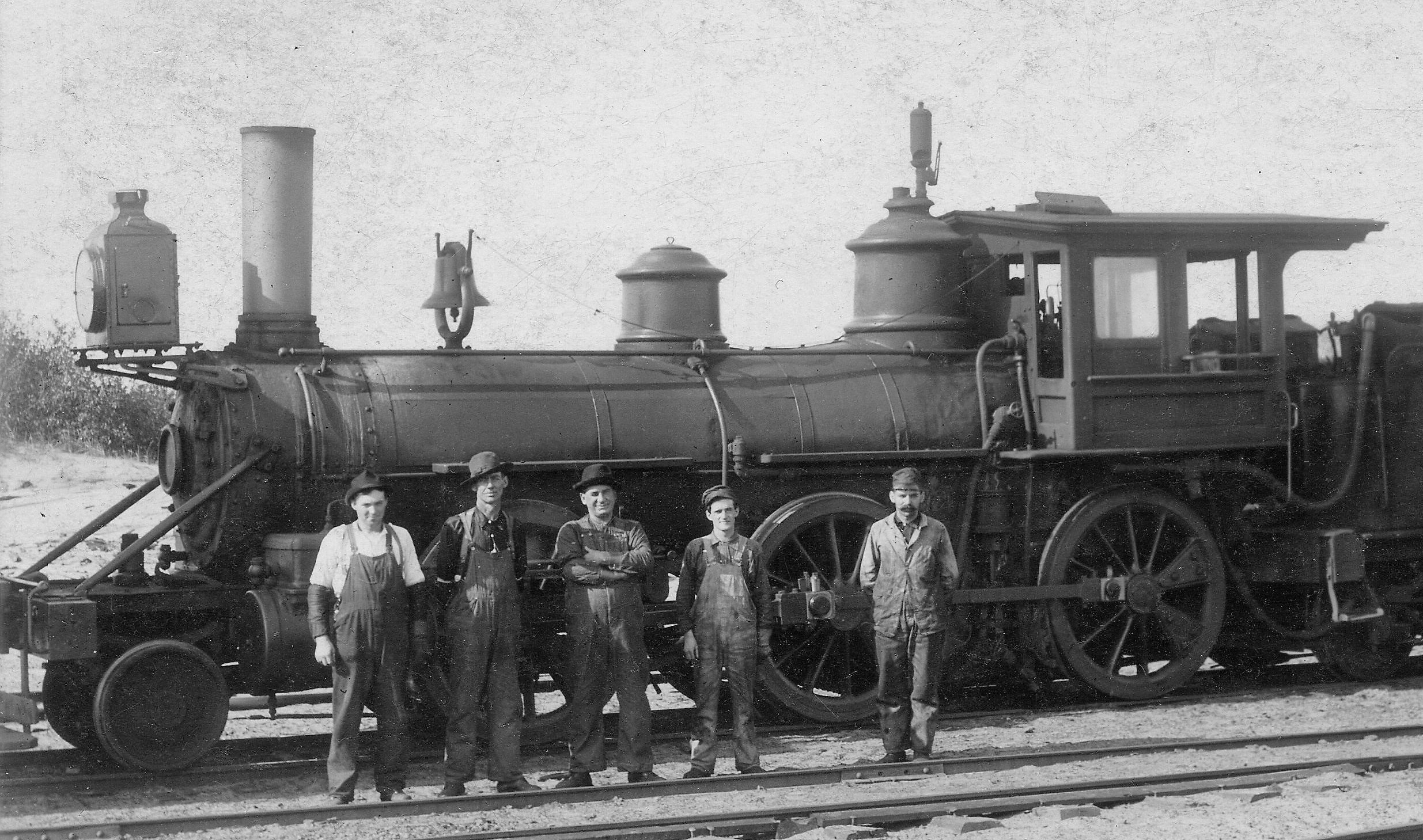 1912 photo of Haywire Locomotive No. 4 and Crew.  Left to Right: Amiel Anderson, Frank Walker, Jack Larien, Edward Labelle (Engineer) and Lavern Niles (Fireman). Niles/Helmka Family Collection.
