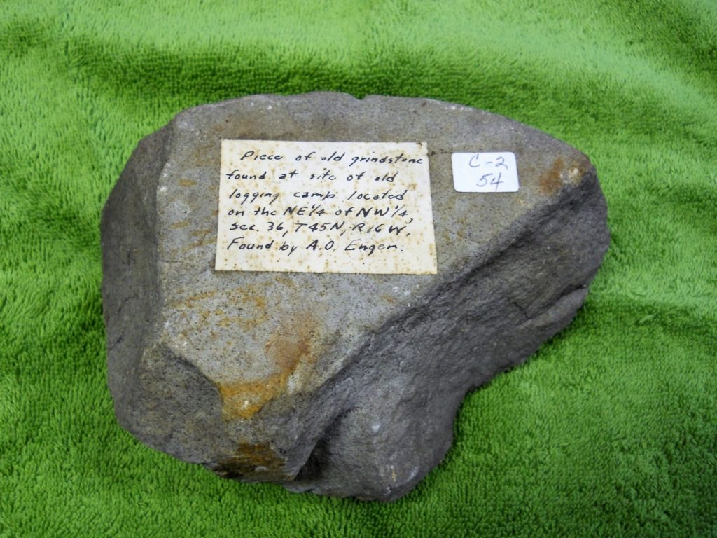 Piece of an old grindstone found at the site of a logging camp located on the NE 1/4 of NW 1/4, Sec. 36, T. 45 N, R. 16 W. The grindstone fragment was discovered by A. O. Enger.