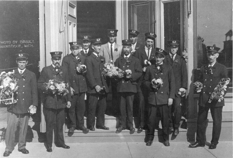 Circa 1906-07 photo of the Manistique Volunteer Fire Department taken in front of the old City Hall building on River Street. Pictured from left to right are:  Ray Stone, Sanford Stone, Seymour Graham, Unidentified, John Durno, Unidentified, Chief Thomas McCullough, Alex Richards Bob Morrison, Leo McGinnis, Allie Bishop and John Hamiel.  